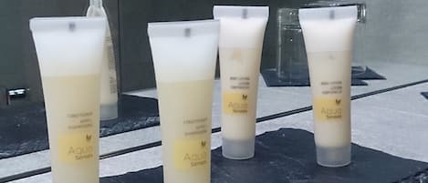 Cuatro botellas de loción corporal Aqua Senses sobre un repisa de mármol.