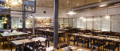 A spacious restaurant with high ceilings, modern lighting, and a variety of seating arrangements.