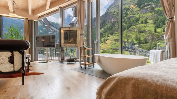Une salle de bain moderne avec une grande baignoire, un plancher en bois et une vue sur un paysage montagneux grâce à de grandes fenêtres.
