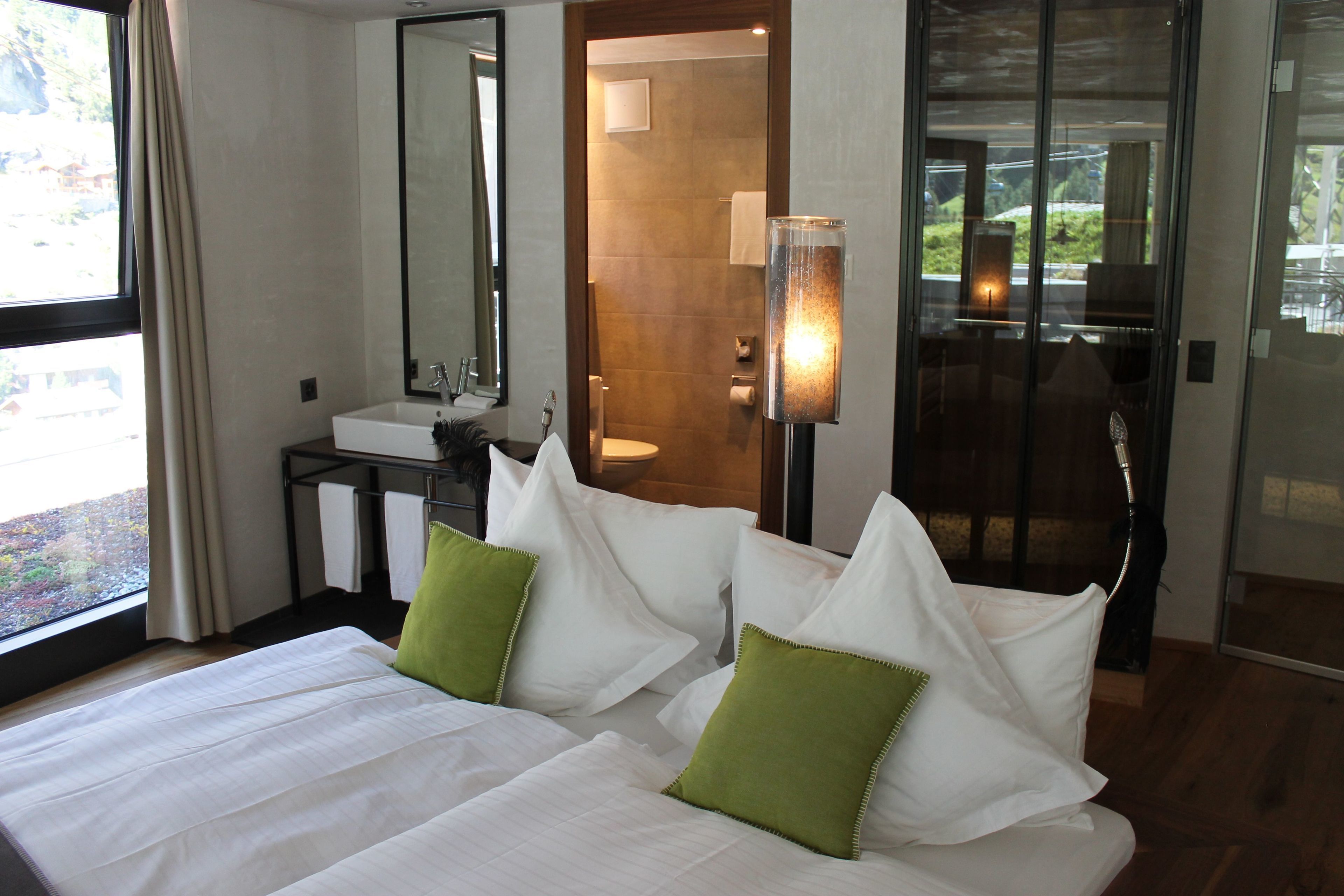 A hotel room with a large bed, a bathroom, and a view of the outdoors.