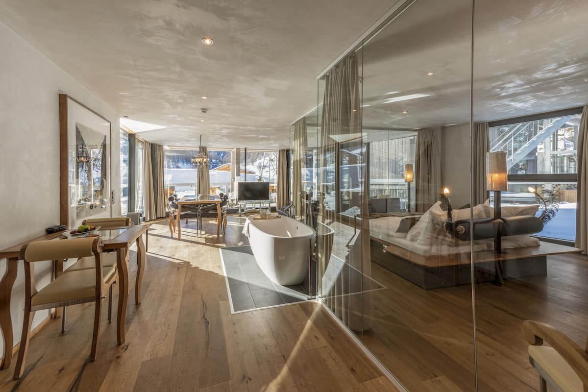 Un intérieur moderne avec une grande baignoire, un canapé et un coin repas doté de chaises en bois.