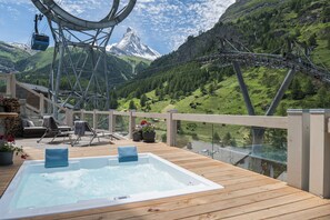 A wooden deck with a hot tub, lounge chairs, and a scenic mountain view. - Matterhorn FOCUS Design Hotel (Zermatt)