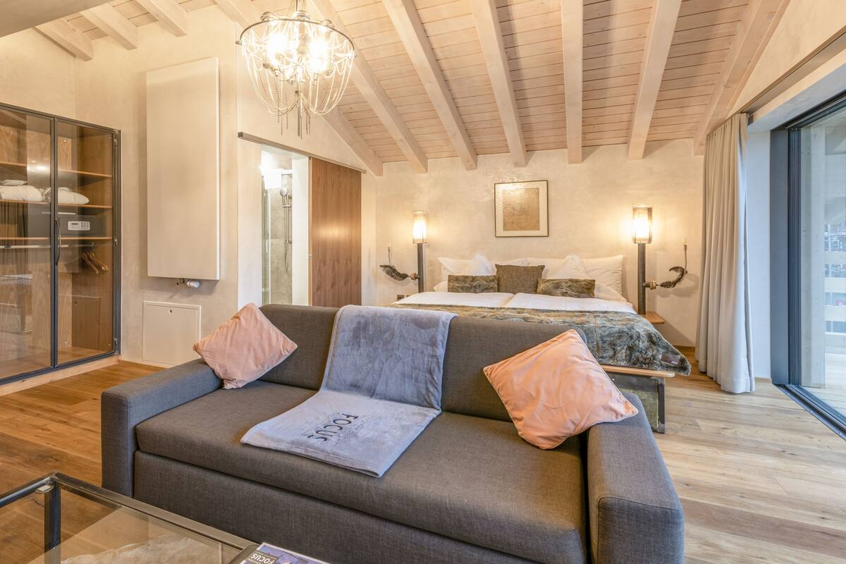 Une chambre moderne avec un grand lit, un canapé et une table basse en verre.