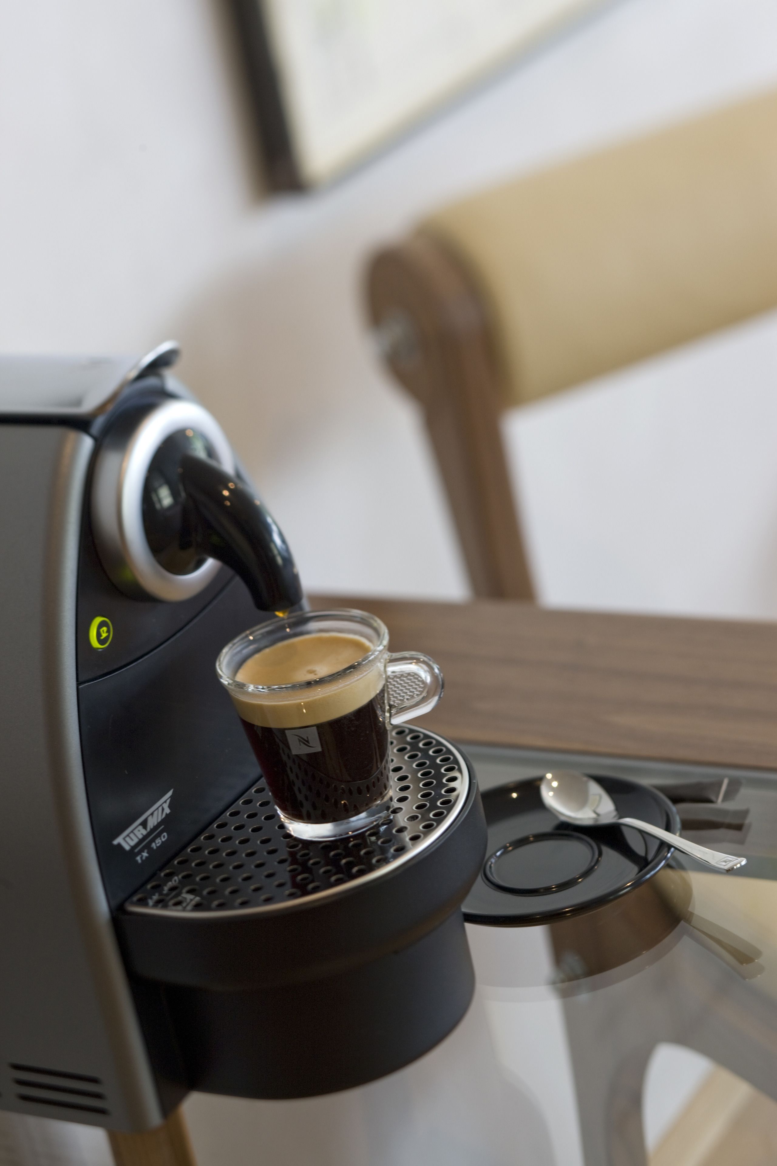 A coffee machine dispensing coffee into a glass cup.