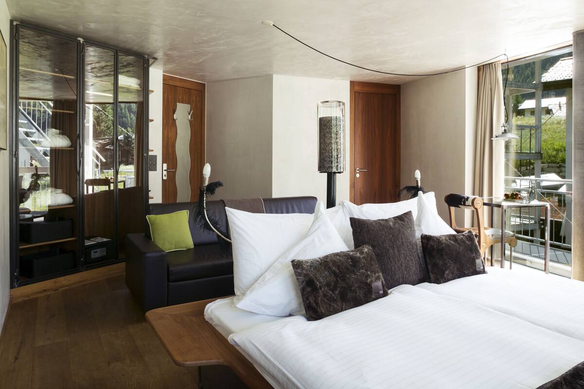 Une chambre d’hôtel moderne, dotée d’un grand lit, d’un canapé, d’un bureau et offrant une vue sur l’extérieur.
