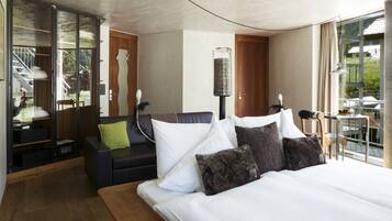 Ein modernes Hotelzimmer mit einem großen Bett, einem Sofa, einem Schreibtisch und Blick ins Freie.