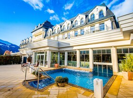 Una piscina techada, una piscina al aire libre, sombrillas