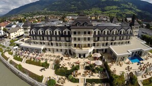 A grand hotel with multiple balconies, a swimming pool, and a scenic mountain backdrop. - Grandhotel Lienz (Lienz)