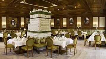 A formal dining room with multiple tables and chairs, a decorative centerpiece, and framed artwork on the walls.