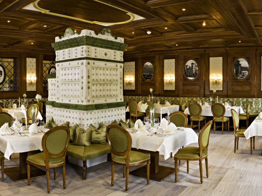 A formal dining room with multiple tables and chairs, a decorative centerpiece, and framed artwork on the walls.