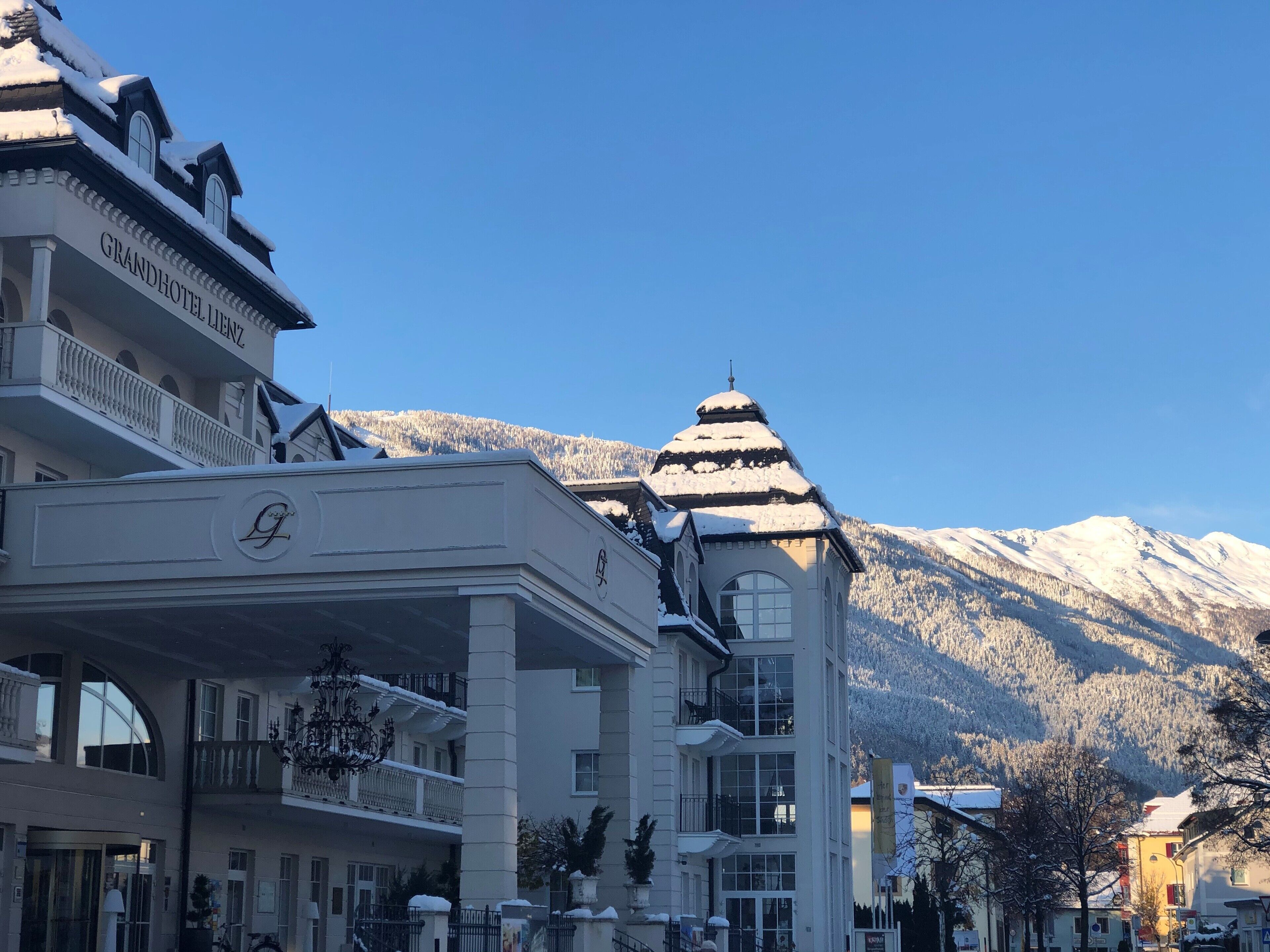 A hotel with a grand entrance, multiple balconies, and a snow-covered mountain backdrop.