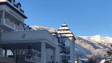 A hotel with a grand entrance, multiple balconies, and a snow-covered mountain backdrop.