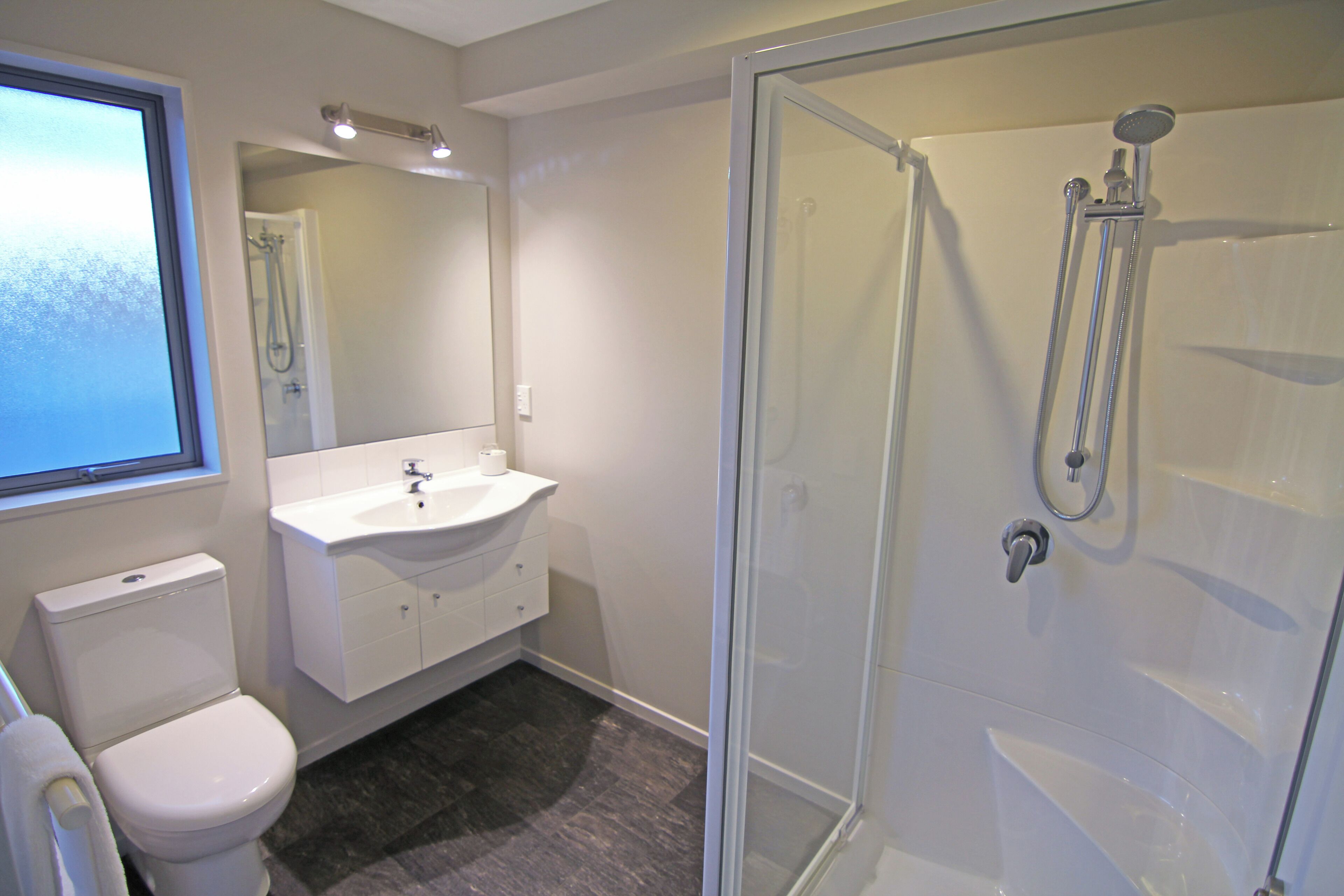 A bathroom with a toilet, sink, and shower.