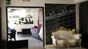 Ett välkomstområde med en vit och guldbrun soffa, en receptionsdisk och en vägg med La Villare Resorts logotyp.