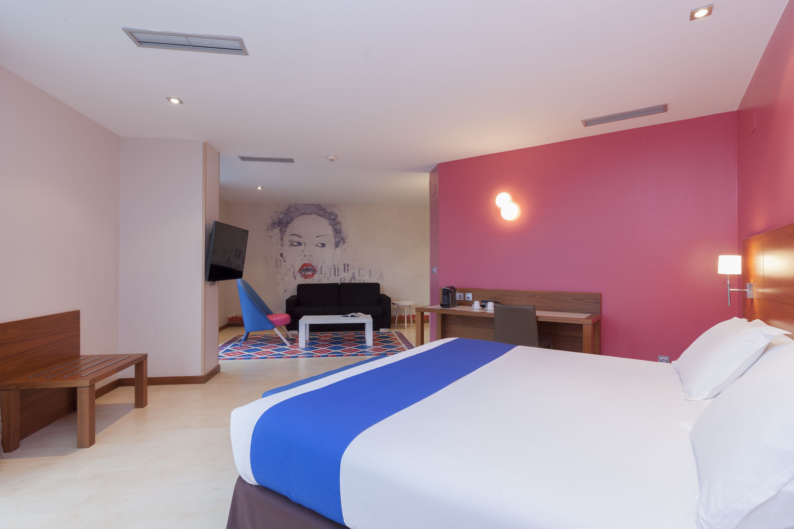 Una habitación de hotel con cama, escritorio, silla y televisor.