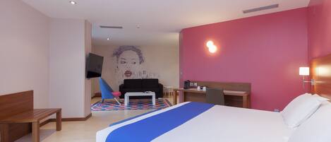 Una habitación de hotel con cama, escritorio, silla y televisor.