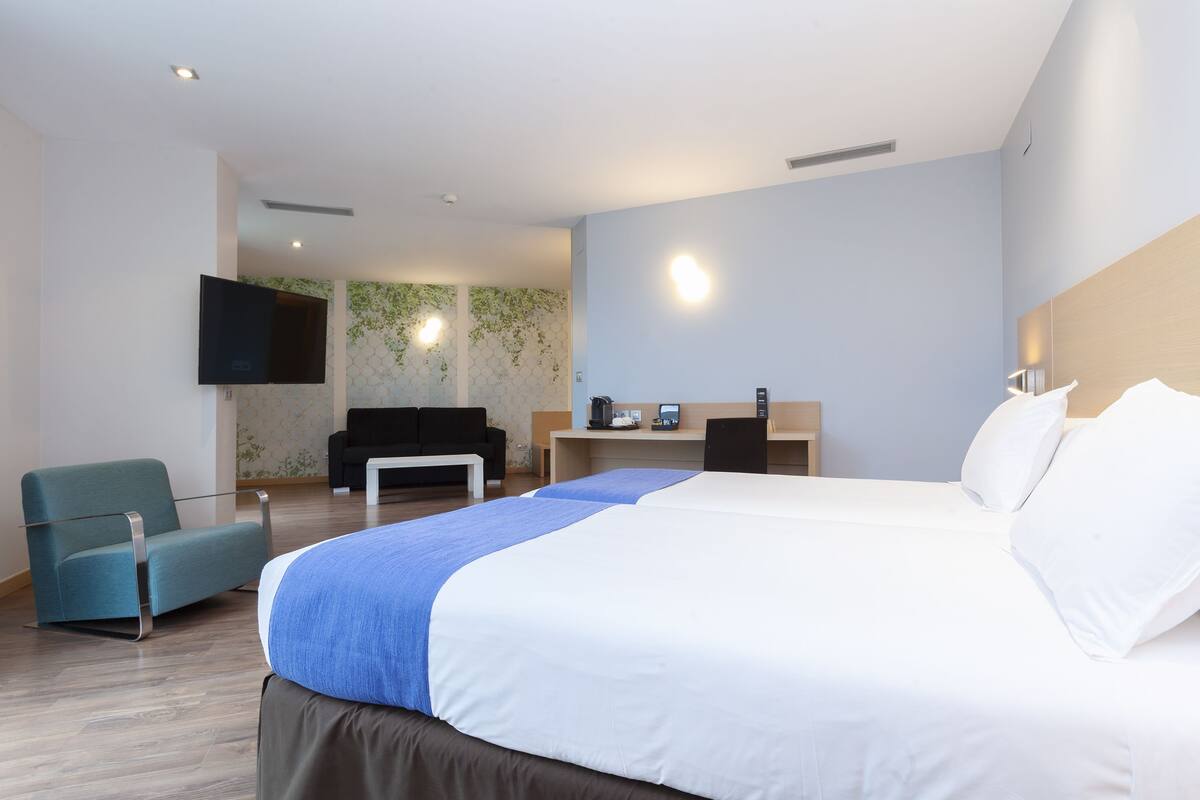 Una camera d'albergo moderna con un letto grande, una scrivania, una sedia e un televisore a schermo piatto montato a parete.