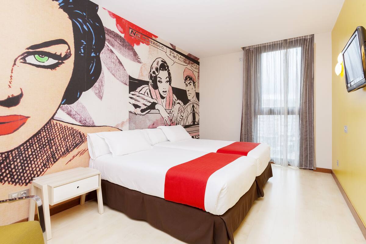 Una camera d'albergo con un letto grande, un comodino e un affresco sulla parete.