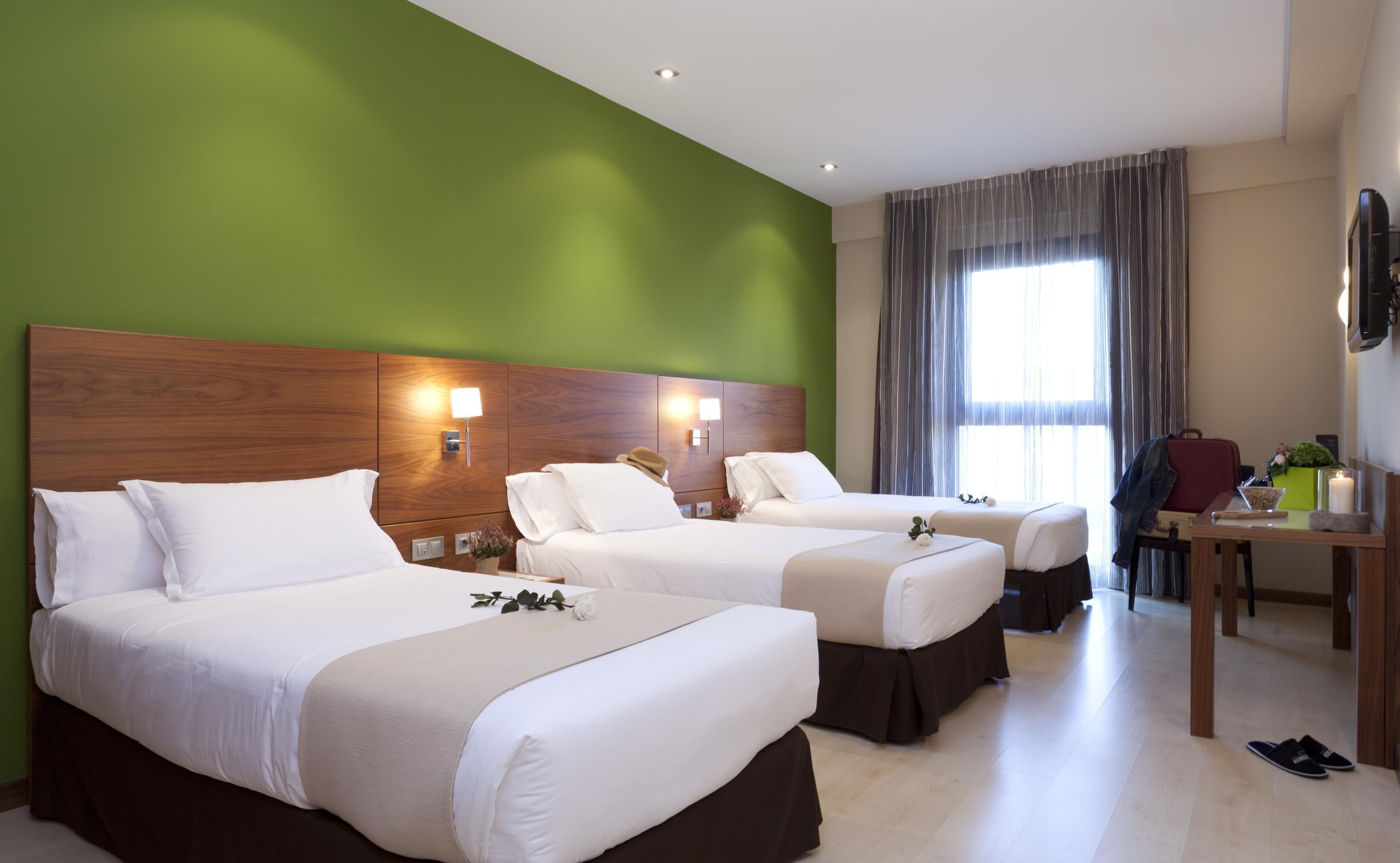 Habitación de hotel con dos camas, un escritorio, una silla y un televisor.