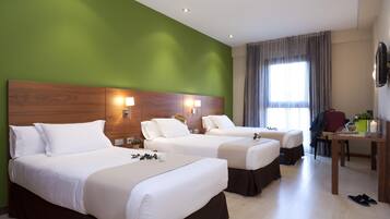 Habitación de hotel con dos camas, un escritorio, una silla y un televisor.
