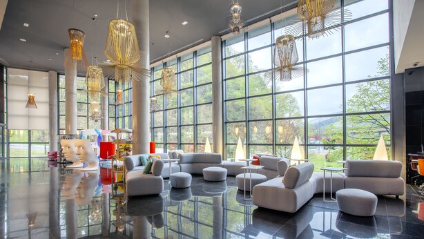Un vestíbulo amplio con ventanas grandes, muebles modernos y luminarias únicas.