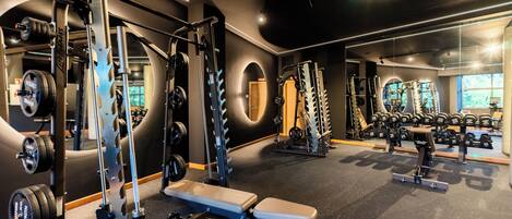 Une salle de sport équipée de matériel de musculation, de bancs et d’haltères.