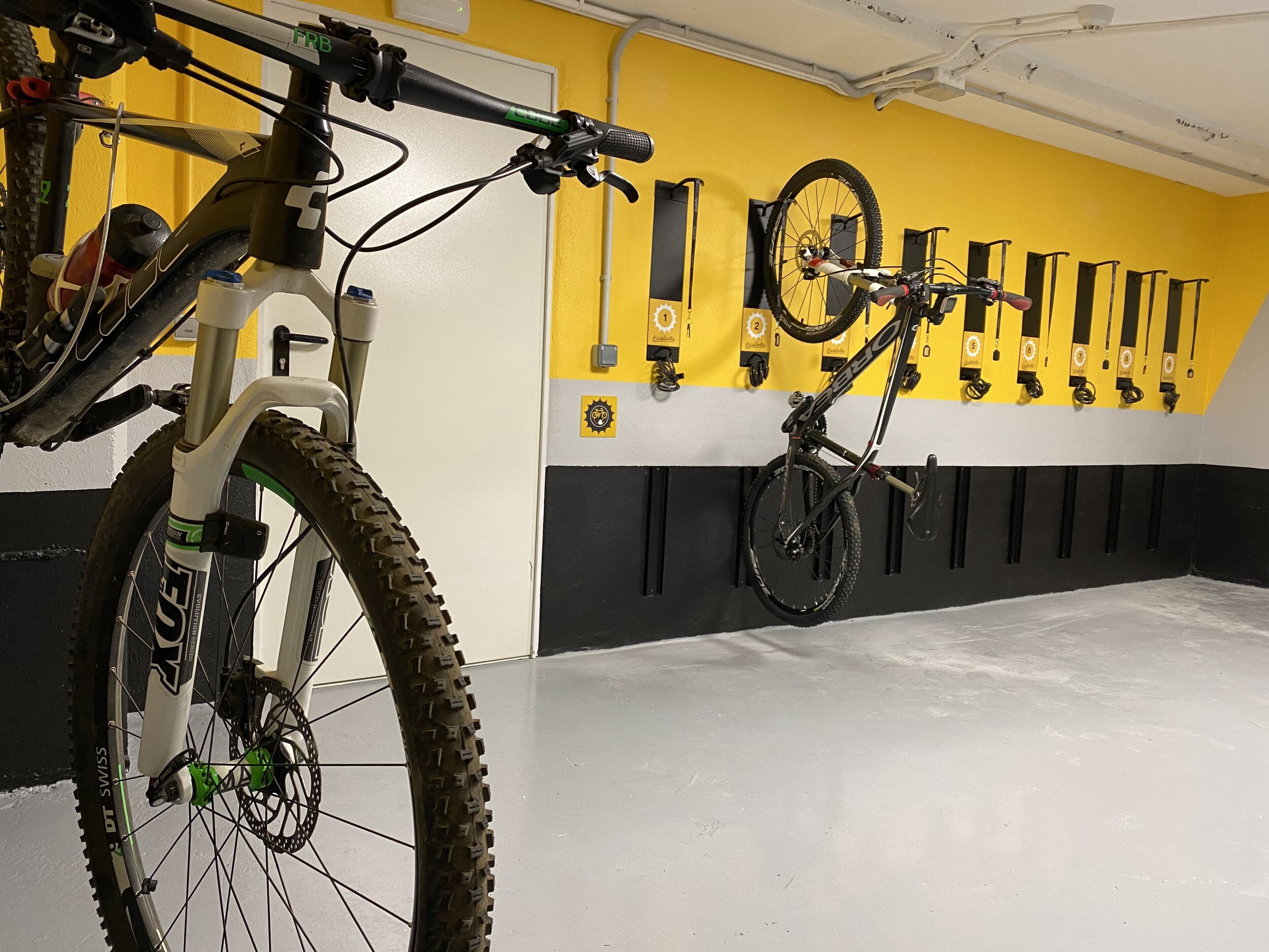 A bicycle storage area with multiple bikes secured on wall-mounted racks.