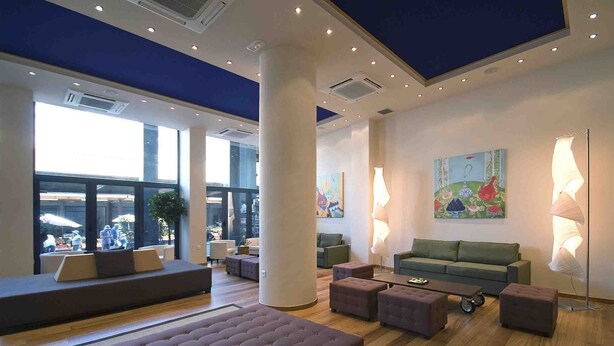 A spacious lobby with a large seating area, a green sofa, and a coffee table. - Athens Center Square Hotel (Athens)