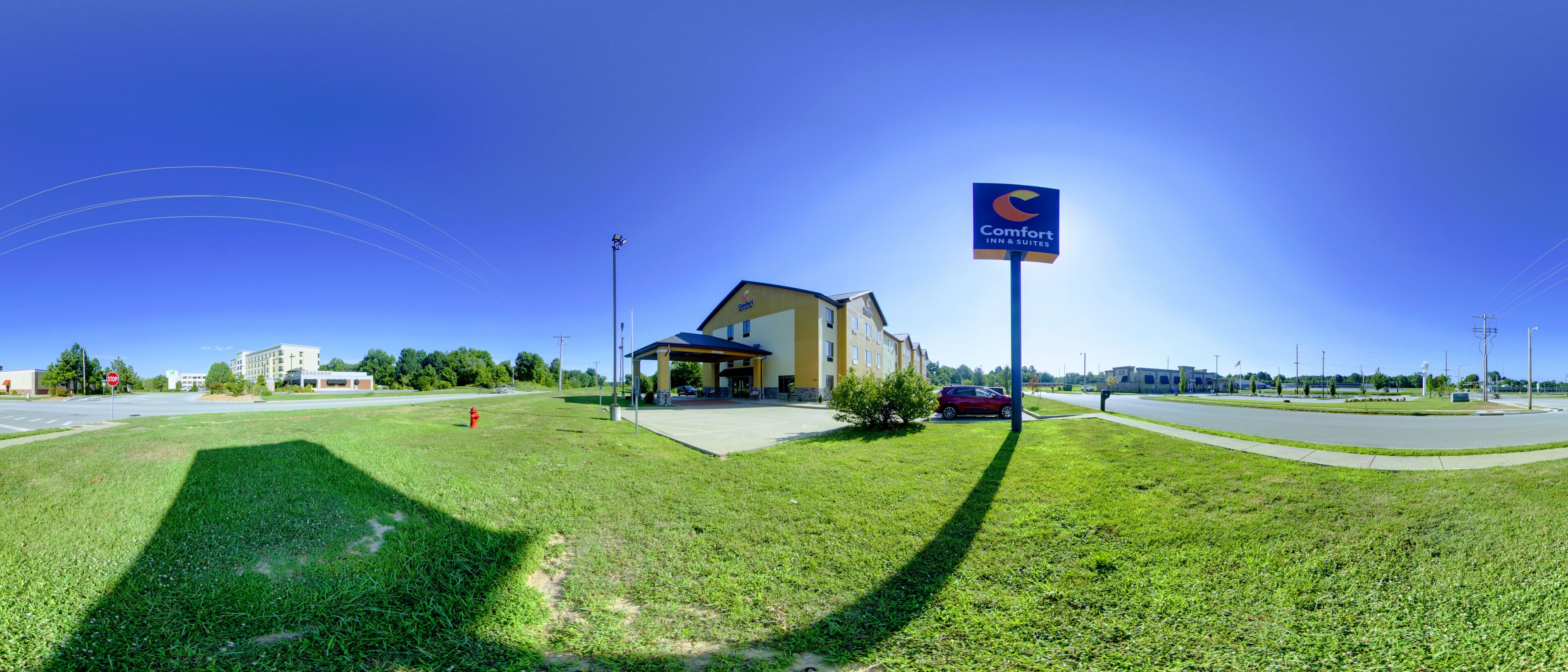 A Comfort Inn & Suites with a clear view of the building's entrance, a parking area, and a grassy lawn.