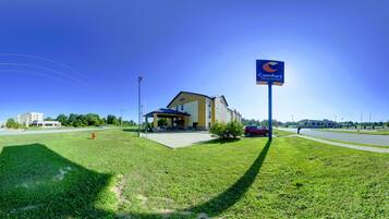 A Comfort Inn & Suites with a clear view of the building's entrance, a parking area, and a grassy lawn.