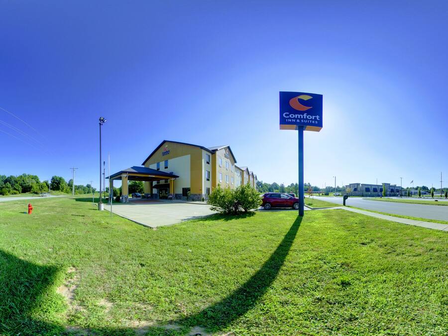 A Comfort Inn & Suites with a clear view of the building's entrance, a parking area, and a grassy lawn.