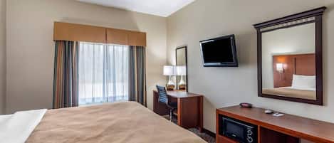 A hotel room with a bed, a desk, a television, and a mirror.