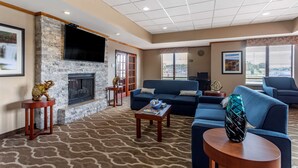A modern living room with a stone fireplace, blue sofas, a flat-screen TV, and a patterned carpet. - Comfort Inn & Suites Carbondale University Area (Carbondale)