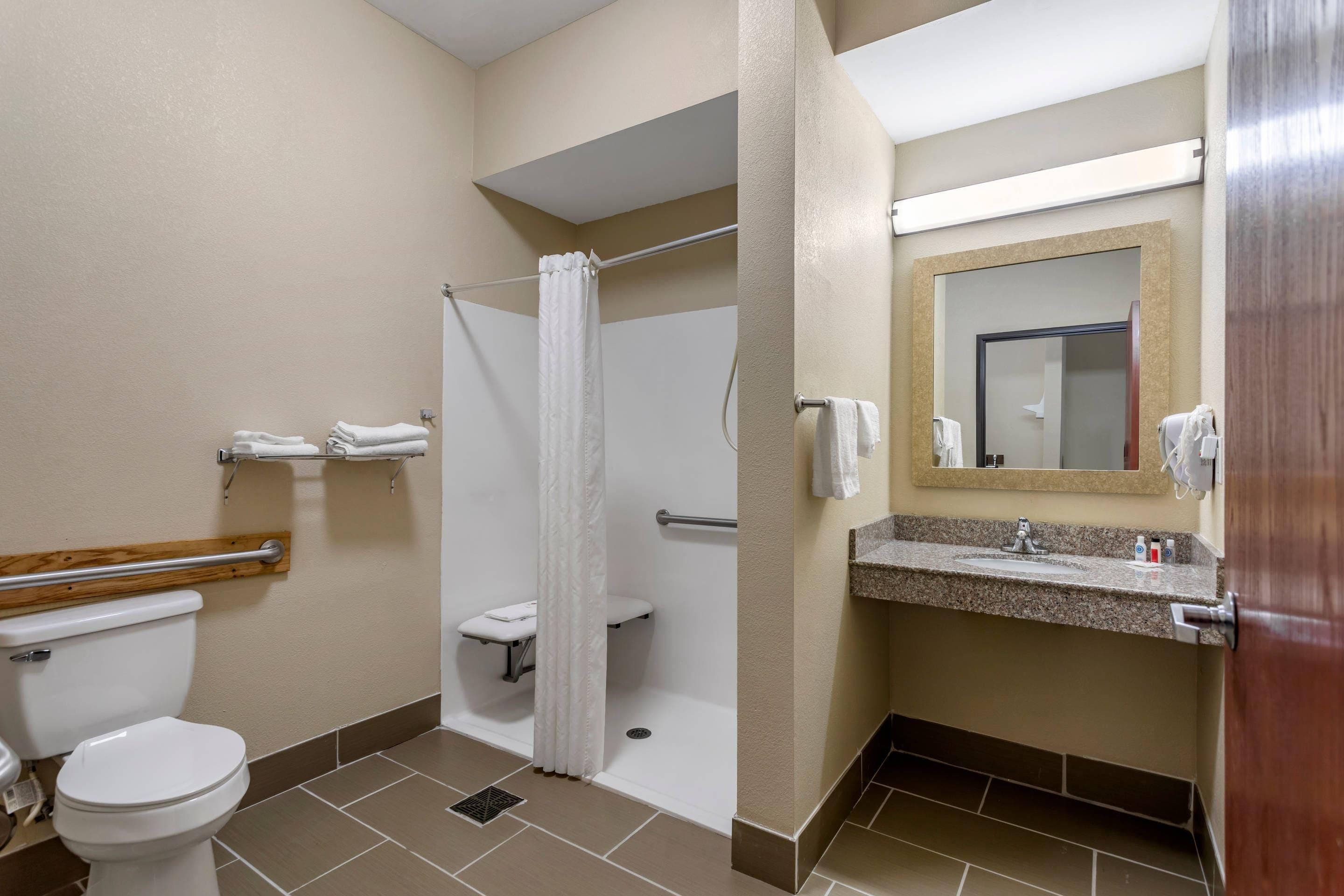 Une salle de bain d’hôtel standard, équipée de toilettes, d’une douche et d’un lavabo.