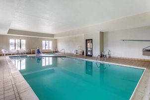 Una gran piscina cubierta con agua cristalina, rodeada de sillas blancas y un suelo de baldosas.