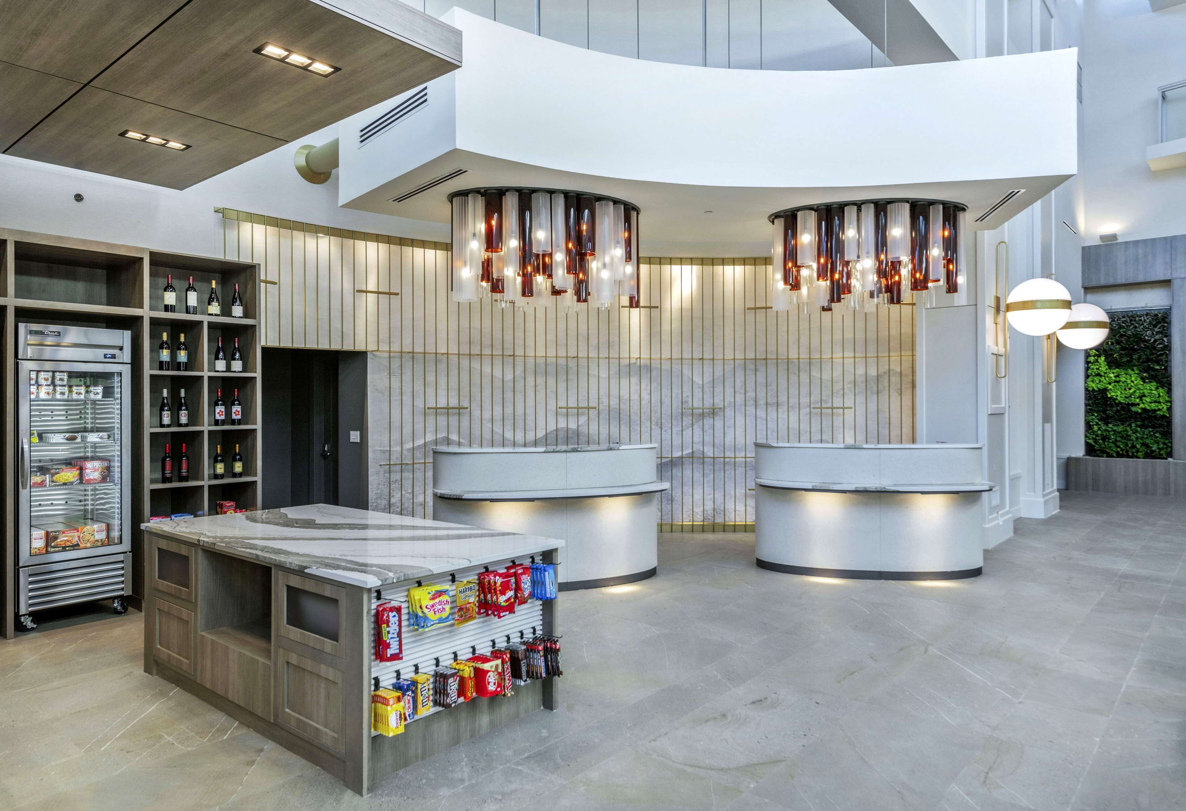 A modern reception area with a marble counter, wine bottles, and a refrigerated display.