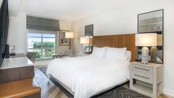A hotel room with a large bed, bedside tables with lamps, a desk, and a view of the outdoors.
