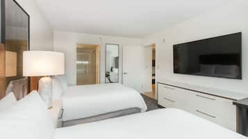 A hotel room with two beds, a TV, a desk, and a mirror.