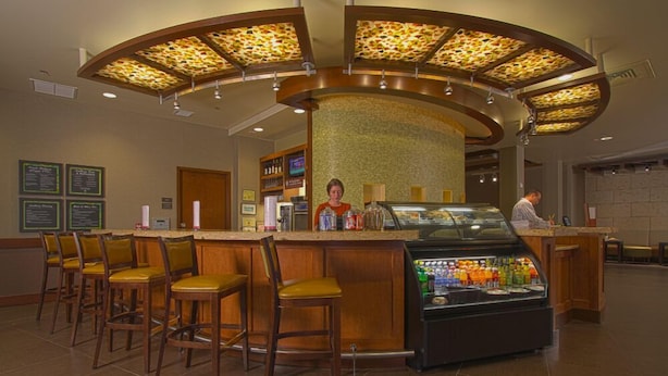 A bar area with a counter, stools, and a refrigerated display case.