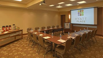 A conference room with a long table, chairs, a projector screen, and a presentation on the wall.
