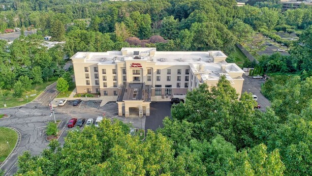 A multi-story hotel with a central courtyard, surrounded by lush greenery. - Hampton Inn & Suites Parsippany/North (Parsippany)
