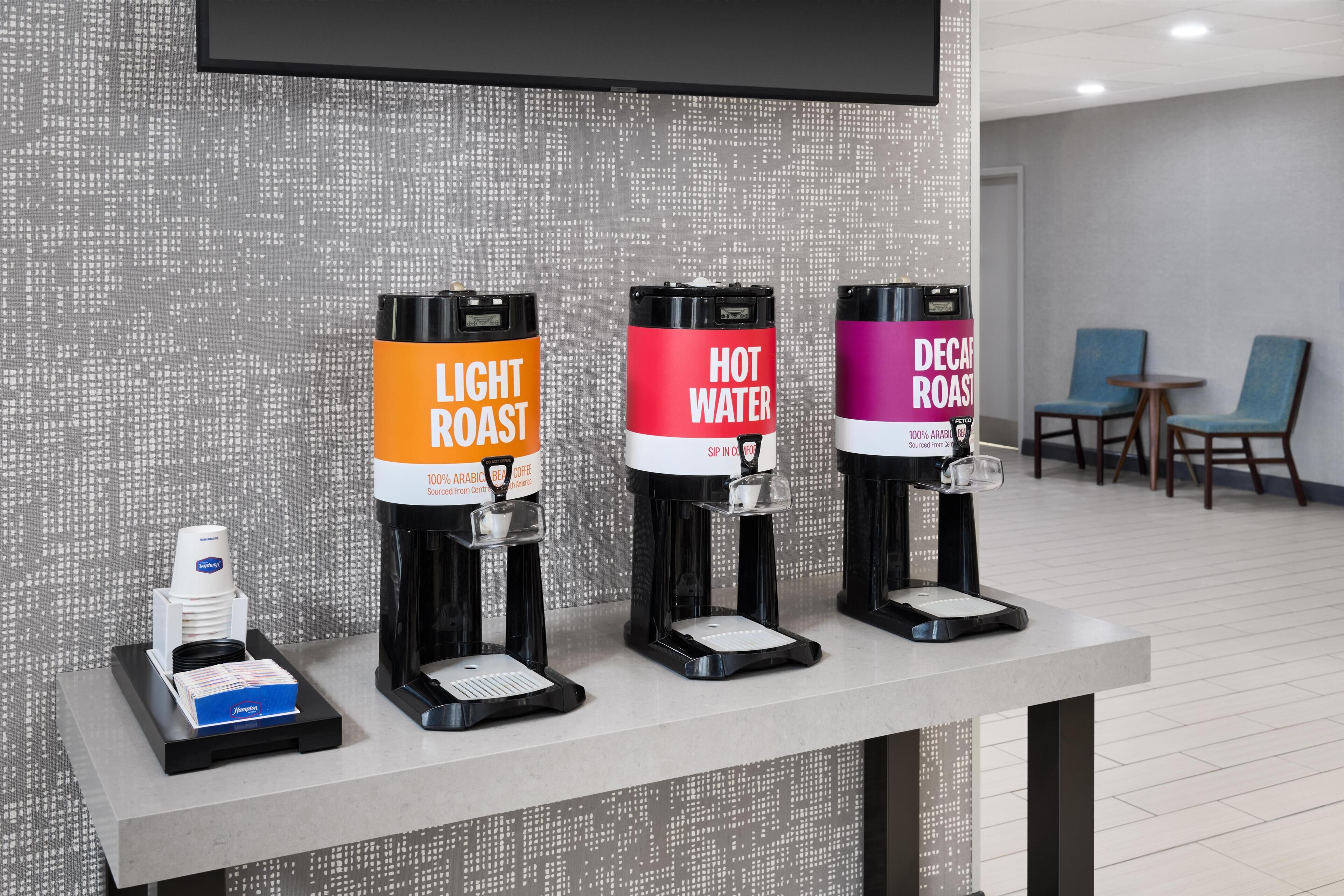 A coffee station with three dispensers labeled 'Light Roast,' 'Hot Water,' and 'Decaf Roast.'