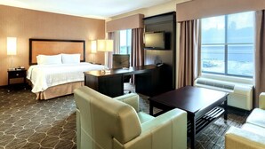 A hotel room with a bed, a desk, a TV, and a large window with curtains. - Hampton Inn & Suites Parsippany/North (Parsippany)
