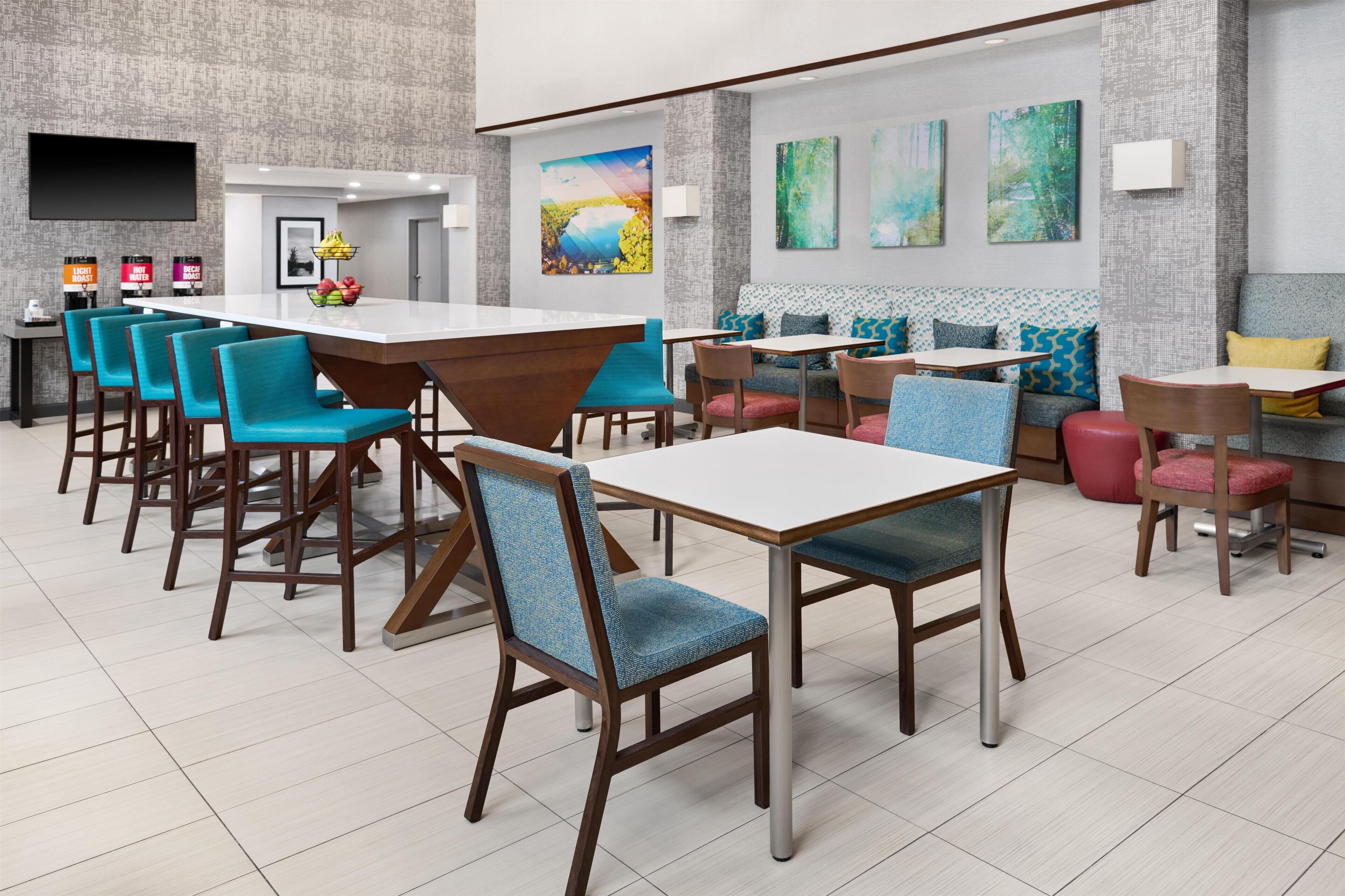 A modern restaurant with a bar area, multiple seating options including bar stools and tables, and artwork on the walls.