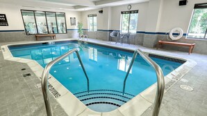 An indoor swimming pool with clear water, a lifeguard chair, and a bench. - Hampton Inn & Suites Parsippany/North (Parsippany)