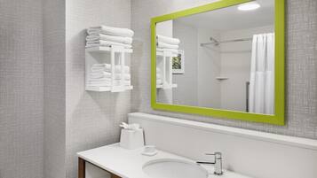 Un baño con un lavabo blanco, un espejo con marco verde y toallas ordenadas.