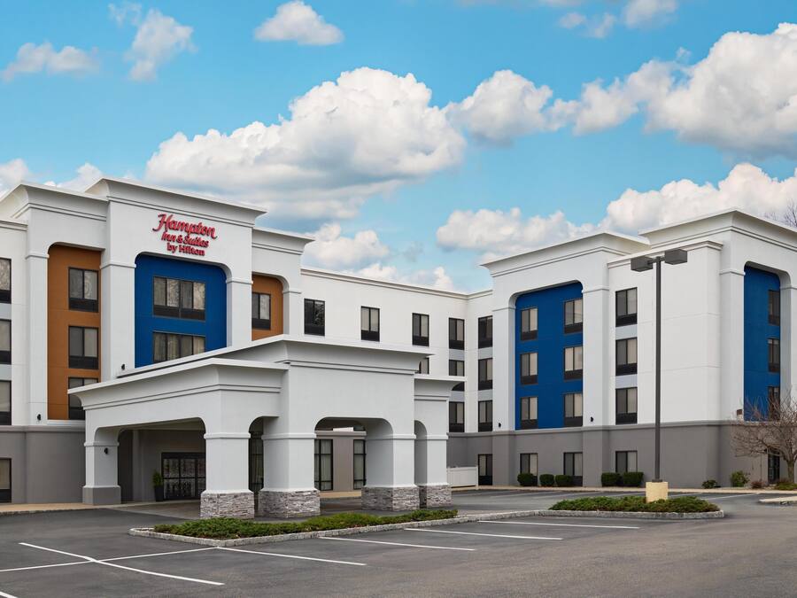 A hotel with a modern facade, multiple entry points, and a parking lot.