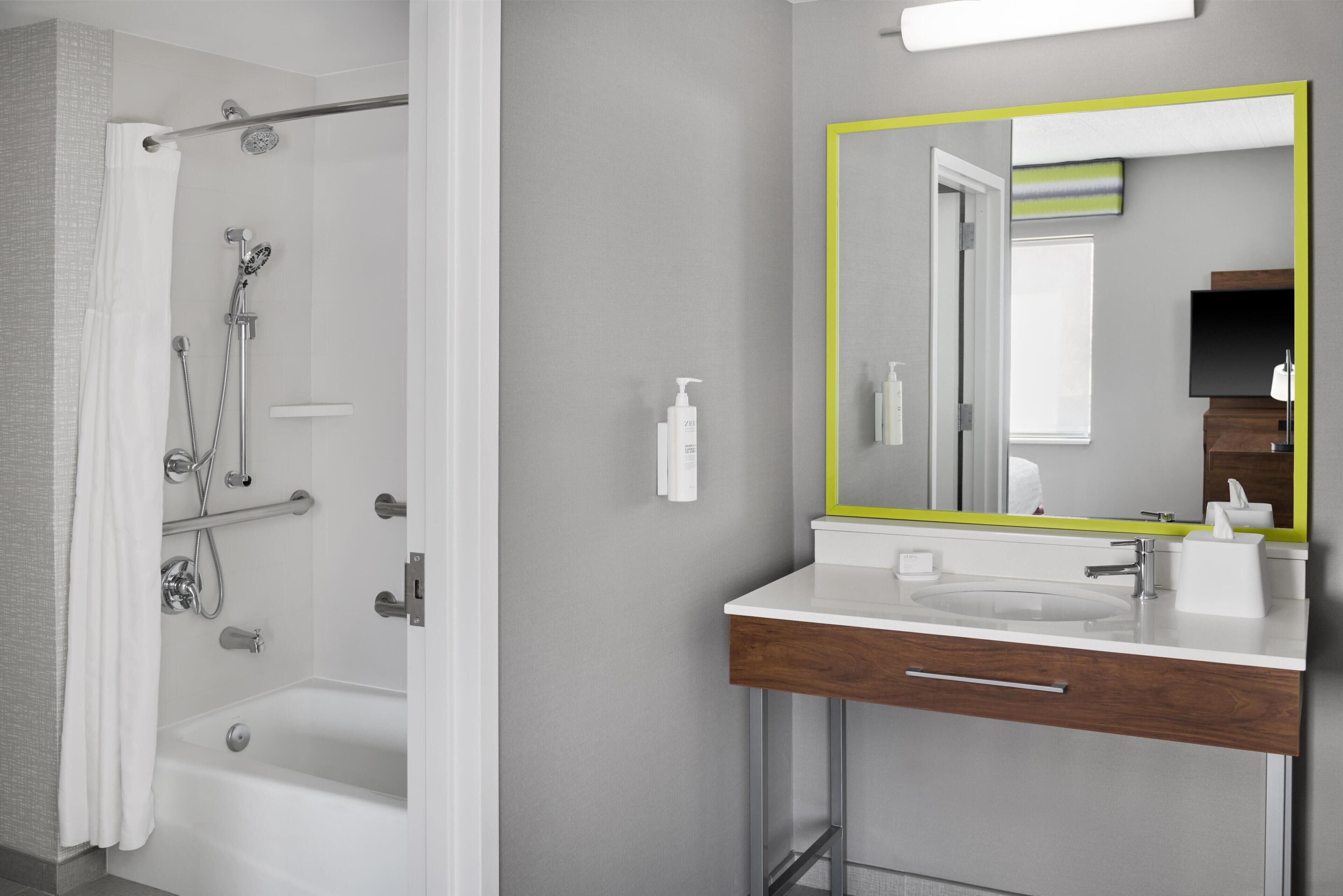 A modern bathroom with a shower, a sink with a mirror, and a toilet.