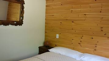 Een kamer met een houten hoofdbord, een nachtkastje en een spiegel.