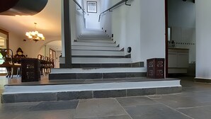Una scala conduce a un piano superiore, dove si intravedono una sala da pranzo e una cucina.